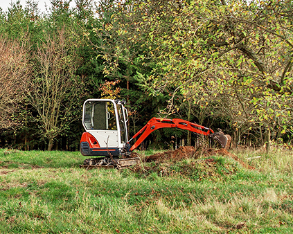 Excavator digging in grassy field